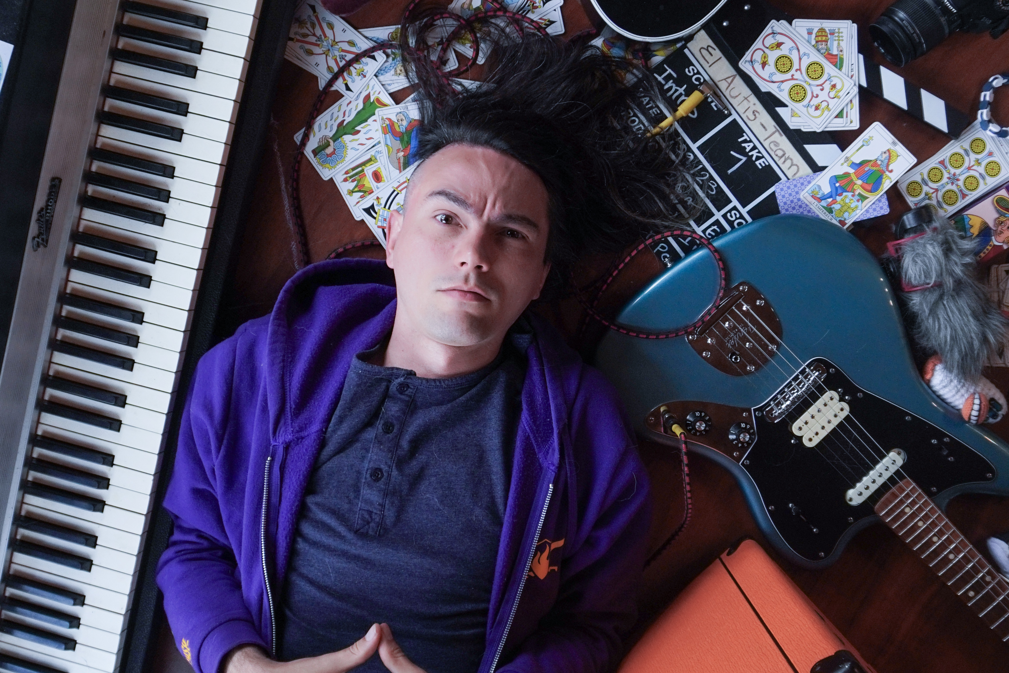 Alvinsch, guía de Lumen Umbra, rodeado de cartas de Tarot, un piano Rhodes, una guitarra eléctrica y una claqueta de cine